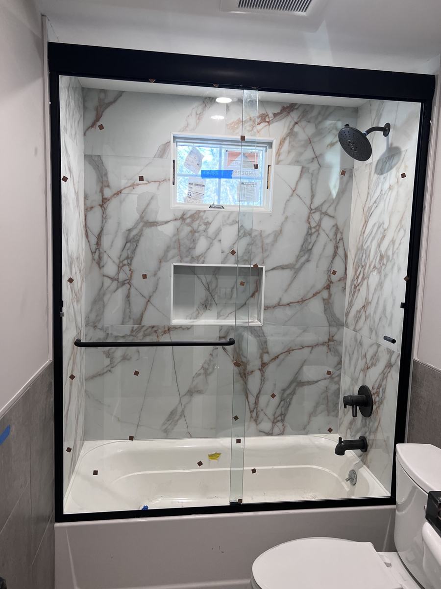 Semi-frameless sliding shower door with matte black hardware